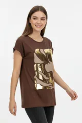 Remera de algodón blanca, de corte holgado, manga corta con vuelta y cuello redondo. Cuenta con un estampado frontal abstracto con trazos en tonos marrón y foil dorado.
