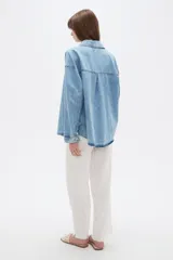 Campera de jean de corte holgado, con cuello camisero, cierre frontal con botones metálicos y mangas largas.