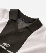 Suéter de punto con diseño a rayas verticales en bloques de color verde oscuro y gris claro. Presenta cuello polo, manga larga con puños ajustados y bordado con lettering Worldmoment en el pecho.