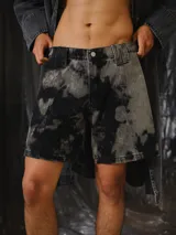 Short unisex de denim con lavado efecto tie-dye en negro y gris, de corte recto y relajado, largo medio y recortes verticales en el delantero.