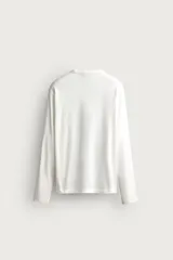 Camiseta de manga larga color azul con cuello redondo, corte relajado y pequeño parche gráfico bordado en el pecho.