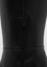 Bota de caña alta confeccionada en piel bovina, con diseño de punta fina y tacón de bloque. Presenta un acabado liso y cierre lateral.