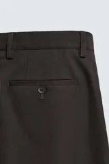Pantalón de corte regular fit confeccionado en tejido mezcla de algodón. Presenta cintura con detalle de pliegues en el delantero, bolsillos frontales y bolsillos traseros de vivo con botón. Cierre frontal con cremallera y botón.