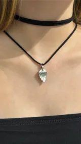 Gargantilla tipo choker compuesta por una cinta negra de tela y un dije metálico plateado con forma de hoja.