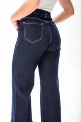 Pantalón de jean azul oscuro de corte ancho, con cintura alta, bolsillos delanteros y traseros con costuras blancas a contraste, y dobladillo ancho.