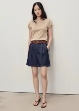 Short denim de tiro medio en color azul oscuro, con diseño recto, pinzas delanteras, bolsillos laterales y traseros, y cierre frontal con cremallera y botón.