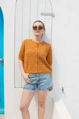 Saco tejido calado color ocre, con mangas al codo y botones de coco. Tiene grifa de cuero en la espalda.