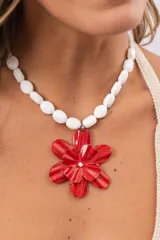 Collar corto de cuentas blancas con un gran dije colgante en forma de flor roja.