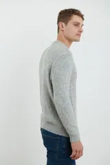 Sweater de tejido de punto color beige claro, con diseño de trenzas (aranes) en el frente y mangas de punto liso. Tiene cuello redondo.