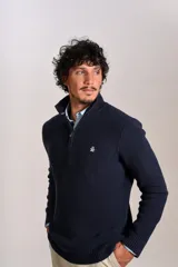 Sweater de punto acanalado color azul marino, con cuello alto y cierre frontal parcial. Presenta el logo de la marca bordado en el pecho y puños con terminación elástica.