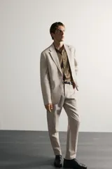 Pantalón de traje regular fit de lino color verde militar, con bolsillos laterales y bolsillos traseros de doble vivo con botón. Cierre frontal con cremallera y botón.