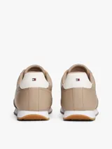 Zapatillas de corte bajo Tommy Hilfiger confeccionadas en piel napa color beige. Presentan paneles con mezcla de texturas, cordones tonales, suela de EVA blanca y detalle de contraste en el talón. Incluyen logo metálico de la marca en el lateral.