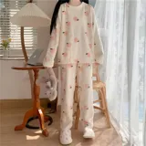 Conjunto de pijama de dos piezas confeccionado en plush suave, compuesto por una remera de manga larga y pantalón largo. Presenta un diseño estampado de duraznos sobre fondo color crema.