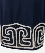 Pollera recta de largo midi en color azul marino, confeccionada en tejido de cambraia de algodón y lino. Presenta un bordado geométrico en color crema en el ruedo, cierre de cremallera y abertura central en la parte trasera.