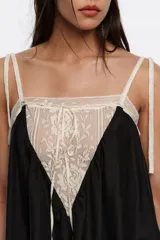 Vestido largo negro de corte holgado, con tirantes finos y detalle de encaje en contraste de color crudo en el escote delantero y en el bajo.