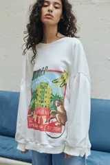 Buzo oversized color blanco off-white, con sisas caídas, mangas con detalle de tabla y estampa central con diseño gráfico estilo vintage de un hotel y un mono.
