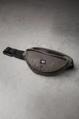 Riñonera de corderoy color gris oscuro con correa ajustable negra y cierre frontal con cremallera. Incluye parche bordado con logo de la marca en el frente.