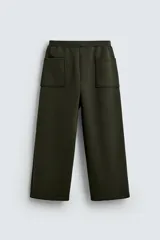Pantalón de corte wide fit confeccionado en tejido técnico con efecto neopreno. Presenta cintura elástica ajustable con cordón, perneras anchas con costura frontal, bolsillos laterales y bolsillos traseros de plastrón.