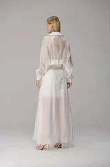 Chaqueta corta de organza en color blanco, con diseño semitransparente, cierre frontal con cremallera, cuello clásico y dos bolsillos frontales con solapa.