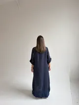 Vestido largo azul oscuro con diseño asimétrico que combina un lado liso con un lado estampado de hojas, manga corta y bolsillo frontal aplicado.