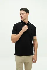 Remera polo negra con cuello clásico y mangas cortas con borde blanco. Tiene un logo pequeño bordado en el pecho.