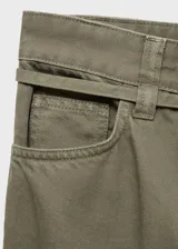Pantalón estilo jeans de corte wide leg, color verde militar, con tiro medio, cierre frontal de cremallera y botón, cinco bolsillos y cinturón fino decorativo en la cintura.