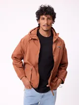 Campera impermeable Rusty con capucha, confeccionada en nylon. Presenta cierre frontal con botones a presión, bolsillos delanteros con solapa y puños elásticos.