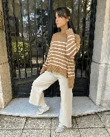 Sweater de tejido de punto con diseño a rayas horizontales en color marrón y blanco, de cuello redondo, manga larga y corte holgado con aberturas laterales en el ruedo.