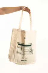 Bolso tipo tote bag color crudo con estampa de una casa en verde.