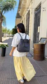 Cartera mochila de diseño versátil y funcional, confeccionada en tela impermeable color negro. Cuenta con compartimento principal con cierre, bolsillo frontal con cierre, asas superiores de mano y correas ajustables para llevar como mochila.