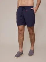 Short de baño azul marino con cintura elástica ajustable con cordón y logo de la marca bordado en rojo en la pierna izquierda.