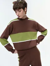 Buzo de punto con diseño de franjas horizontales en azul y blanco sobre fondo negro. Presenta cuello redondo, mangas caídas con puños elastizados y un corte holgado.