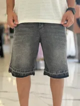 Bermuda de jean de corte baggy, en color gris con efecto acid wash. Presenta diseño de tiro medio y dobladillo desmechado con detalle de doble costura en los bajos.