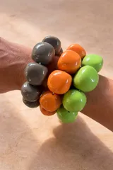 Pulsera elástica compuesta por cuentas de resina de gran tamaño con acabado brillante, disponible en combinaciones de colores gris, naranja y verde.