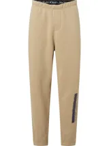 Pantalón de jogging color beige de corte recto, con cintura elástica ajustable con cordón, bolsillos laterales y traseros, puños acanalados y logo de Calvin Klein Jeans estampado en la pierna izquierda.