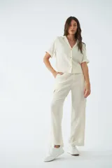 Pantalón cargo de tiro alto y corte recto, confeccionado en viscosa con textura arrugada. Cuenta con bolsillos laterales, cierre de cremallera y botones, y presillas para cinturón.