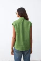 Camisa sin mangas de lino color verde, con cuello clásico, cierre frontal de botones y costura horizontal en el pecho.