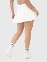 Conjunto deportivo compuesto por una musculosa azul de corte atlético y una pollera blanca plisada de estilo tenista.