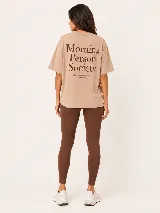 Remera oversize color tostado, con mangas cortas y cuello redondo. Presenta un gran estampado en la espalda con la inscripción "Morning Person Society" y un texto secundario en tipografía más pequeña.