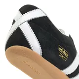 Championes Adidas modelo Tokyo, color negro con las tres rayas distintivas de la marca en blanco y detalles plateados en el talón y la lengüeta. Suela de goma color caramelo.