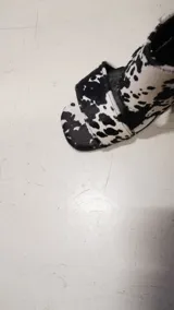 Sandalias de tacón alto y ancho, confeccionadas en piel con acabado de pelo y estampado animal print de vaca en tonos marrones y blancos, con tiras anchas en el empeine.