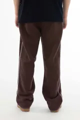 Pantalón de jogging marrón con corte recto, cintura elástica y cordón ajustable. Cuenta con bolsillos laterales y una línea vertical blanca a lo largo de la pierna.