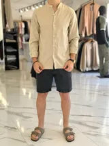 Camisa de lino color beige, de manga larga con puños arremangados y cuello mao. Cuenta con cierre frontal de botones y diseño clásico.