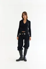 Top de manga larga color verde petróleo, con cuello polo y escote en V pronunciado. Presenta recortes diagonales en el frente y un pequeño bordado en el puño.