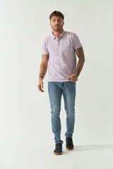 Chomba color lila de manga corta, con cuello polo y cierre de tres botones. Tiene un logo estampado en el pecho y un corte regular.