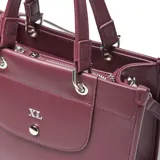 Cartera estructurada mediana de material símil cuero color bordó, con doble manija fija y correa larga regulable y desmontable. Presenta solapa frontal con botón imantado y cierre superior con cremallera metálica.