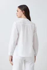 Camisa blanca de manga larga con bordados en el frente y cuello.