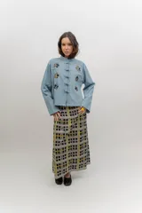 Chaqueta liviana de jean celeste con cuello mao, cierre frontal con alamares y detalle de bordados florales.