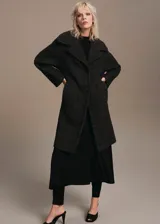 Abrigo largo estilo oversize con diseño de cuadros, cuello con solapa de muesca, cierre delantero con botones y bolsillos laterales.