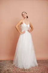 Vestido largo blanco de alta costura, con corset estructurado de tirantes finos con apliques florales y falda amplia de tul con brillo.